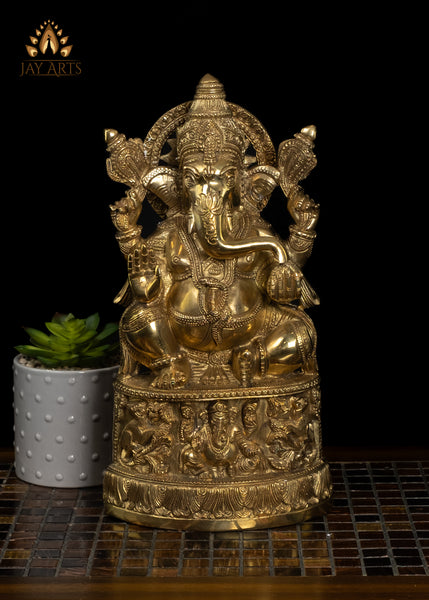 13" Lord Ganesh with Surya Halo seated on a pedestal with figurines of Ganesh and Lakshmi