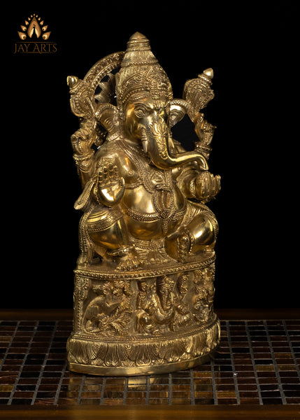 13" Lord Ganesh with Surya Halo seated on a pedestal with figurines of Ganesh and Lakshmi