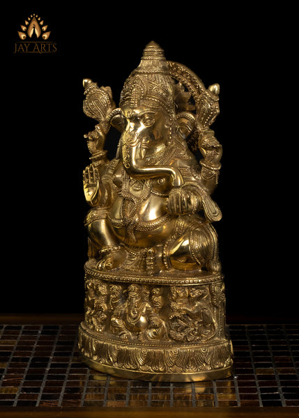 13" Lord Ganesh with Surya Halo seated on a pedestal with figurines of Ganesh and Lakshmi